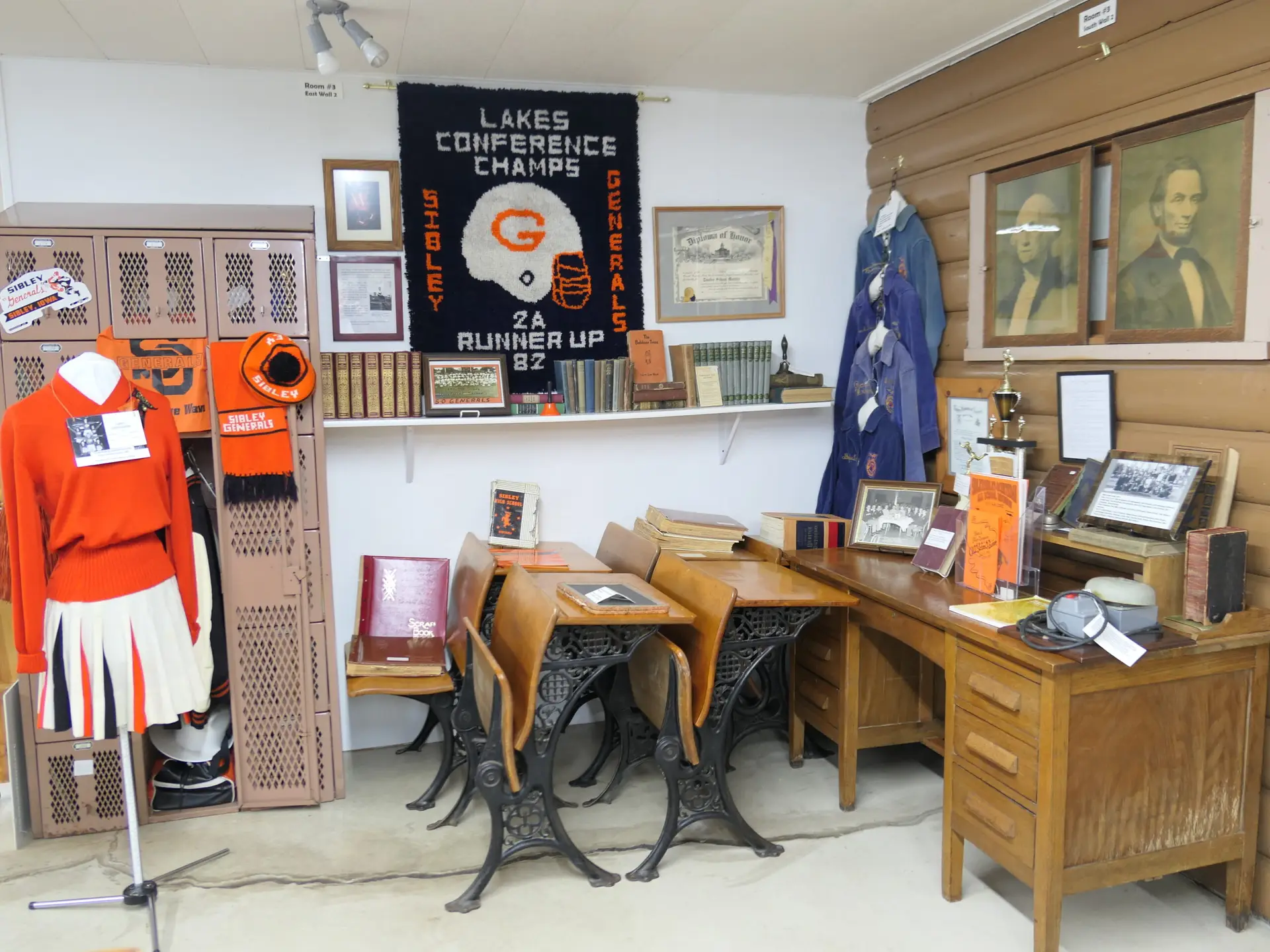 Sibley High School Generals memorabilia display at McCallum Museum in Sibley, Iowa featuring cheerleader uniform, letterman jackets, championship banner, and vintage school desks